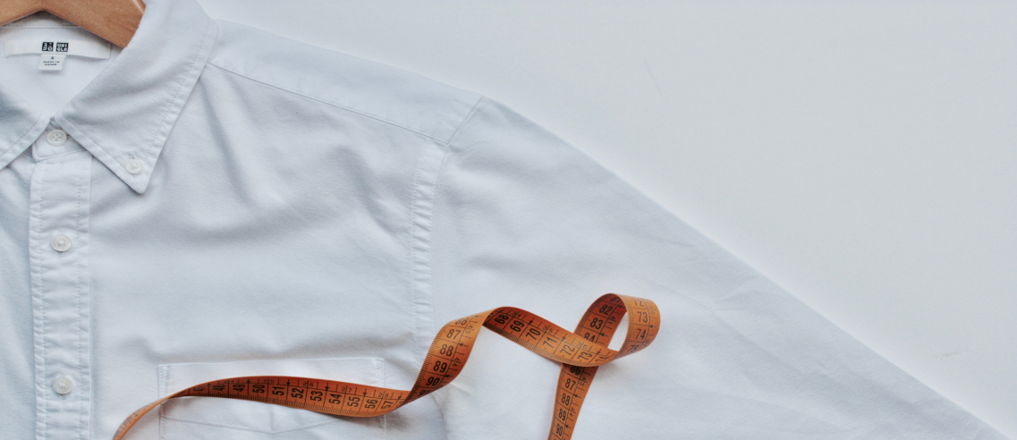 Une chemise blanche avec un ruban de mesure posé dessus.