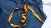 Une chemise bleue avec un ruban de mesure posé dessus.